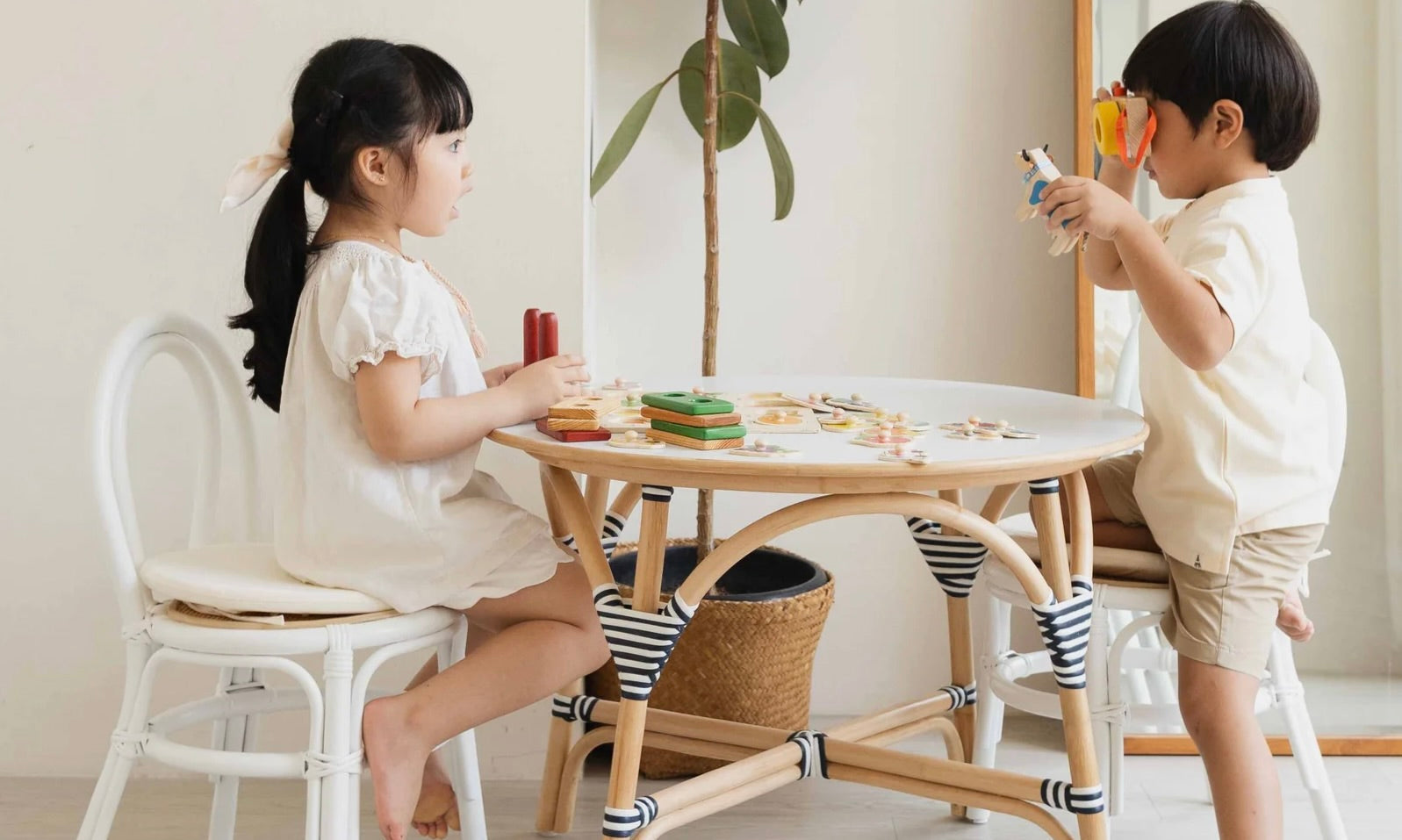 two small kids playing by rattan chairs and table