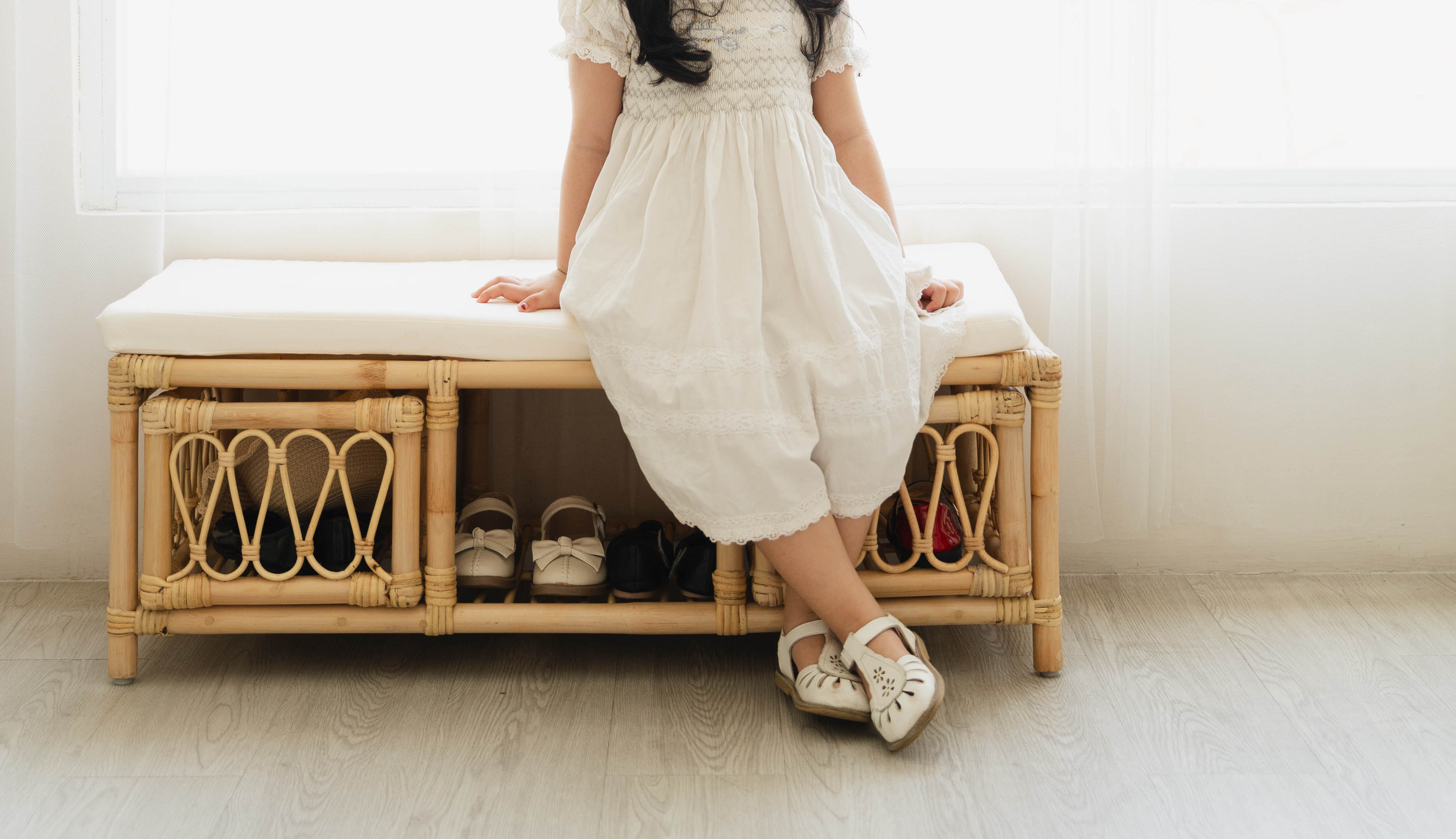 girl sitting on a rattan storage bench