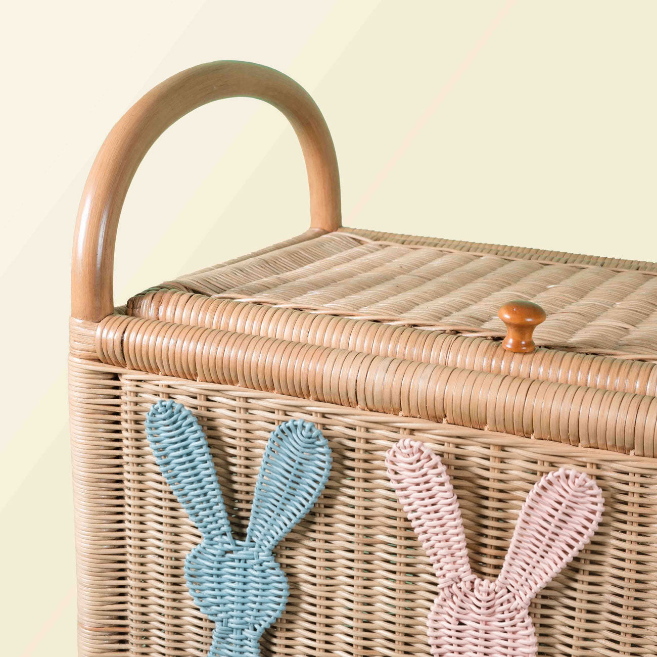 Close-up of rattan wicker trunk with woven rabbit details, integrated handle and lid closure, on a light background.