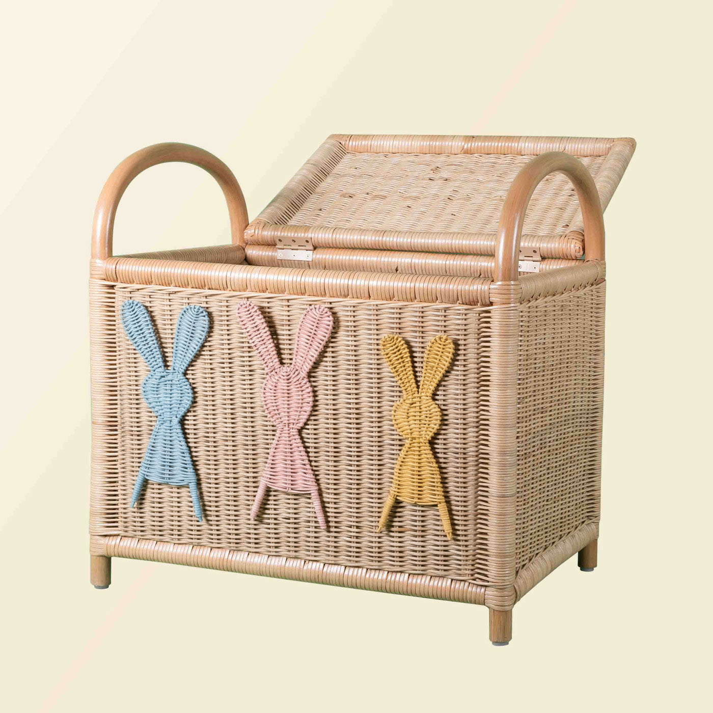 Wicker rattan toy trunk with colorful rabbit decorations and lid open on a beige background