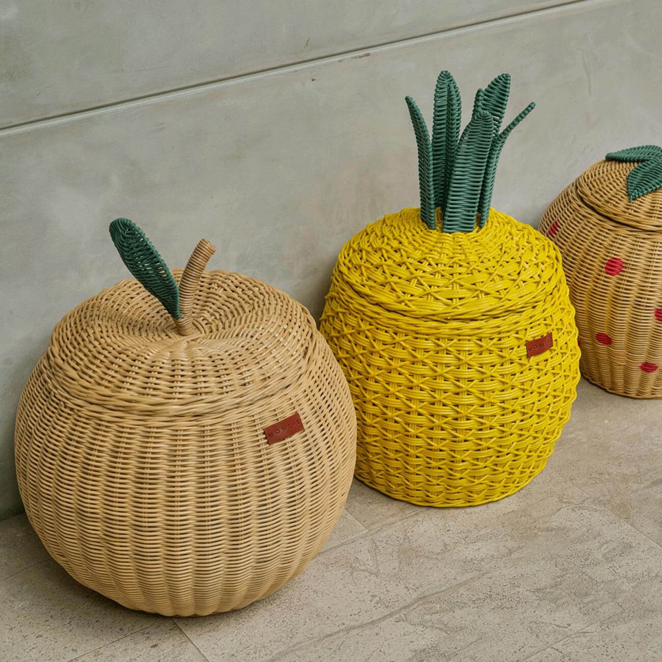 Natural apple rattan storage basket in medium size by MOMIJI displayed alongside yellow pineapple and strawberry rattan storage baskets.