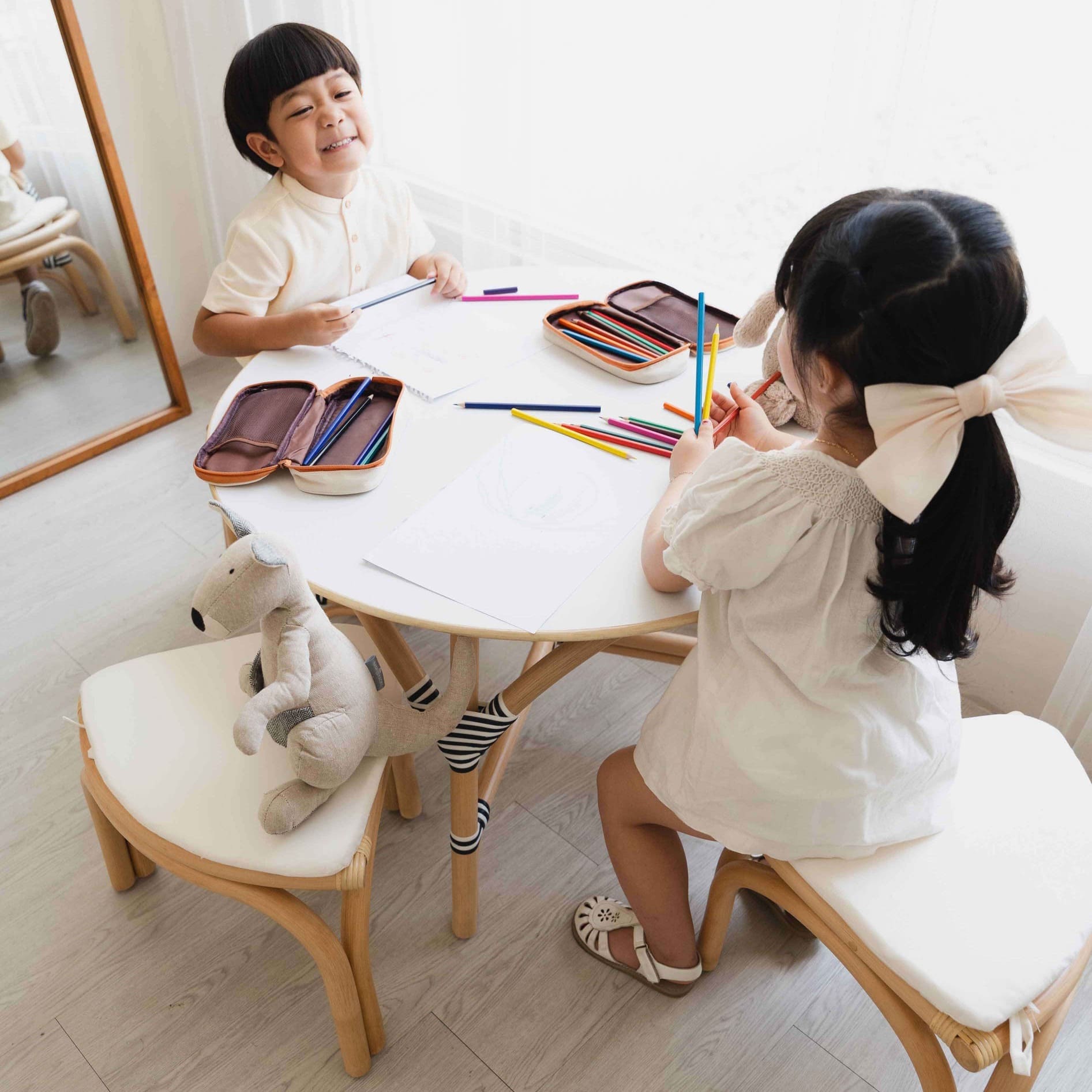 Two children sitting at Aulia Table Set with Stools by MOMIJ around the table with art supplies, smiling and engaged in an activity.