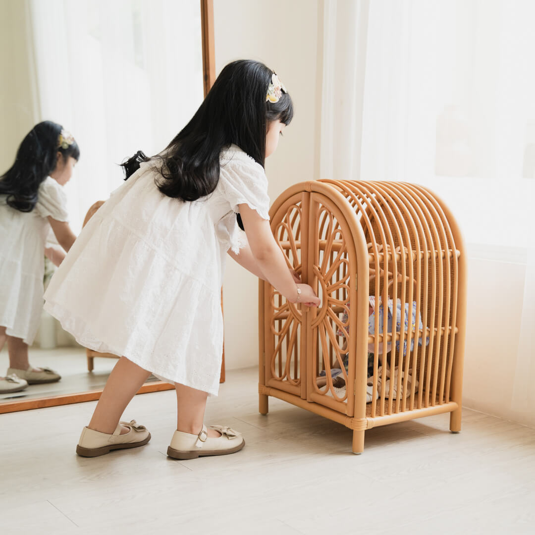 Child holding the door of the Blossom Doll Closet by MOMIJI in a room with a mirror.