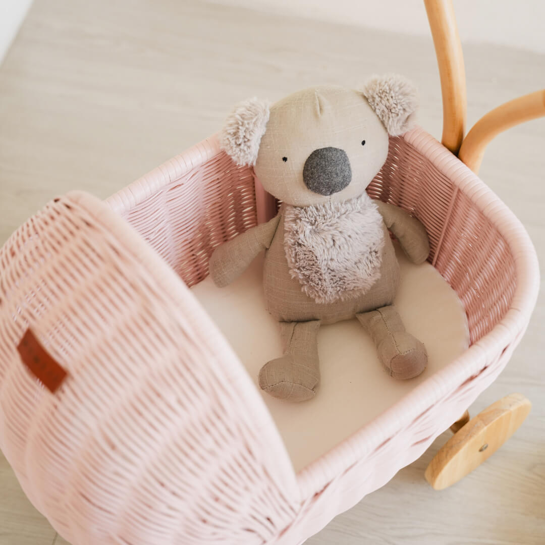 Inside view of a stuffed koala toy placed in the handcrafted pink rattan wicker Colette Doll Stroller by MOMIJI.