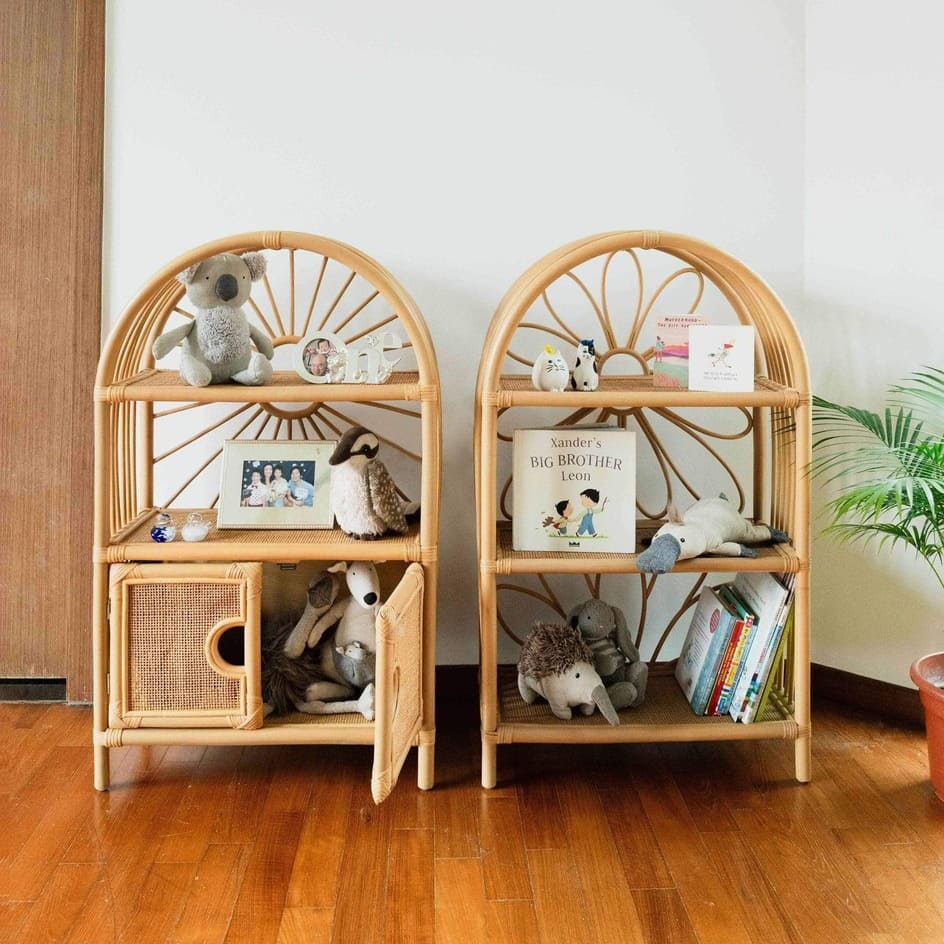 Handcrafted rattan Daisy Arch Shelf by MOMIJI displayed beside rattan cabinet shelves, showcasing three-tier storage for kids toys and books.