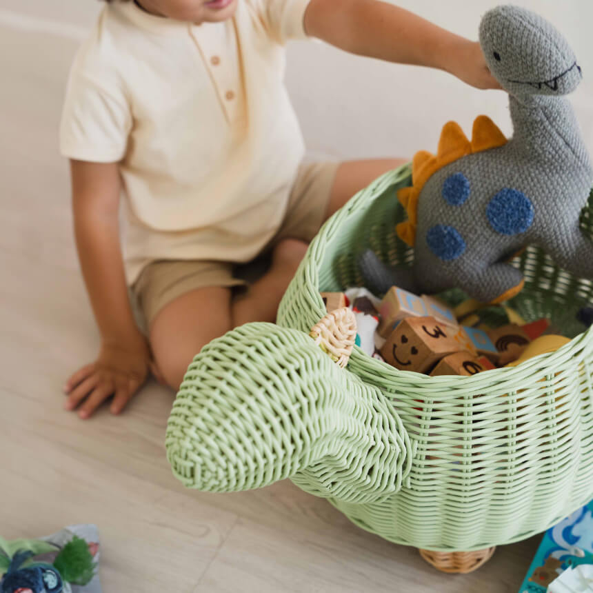 Close up head shot of mint green dinosaur rattan storage basket in large size by MOMIJI with toys inside.