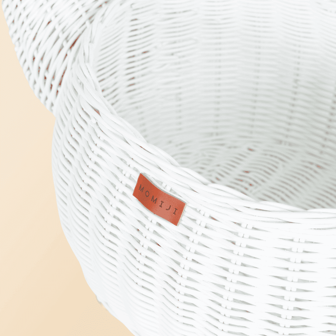 Close up shot of the MOMIJI logo of the white dinosaur rattan storage basket by MOMIJI.