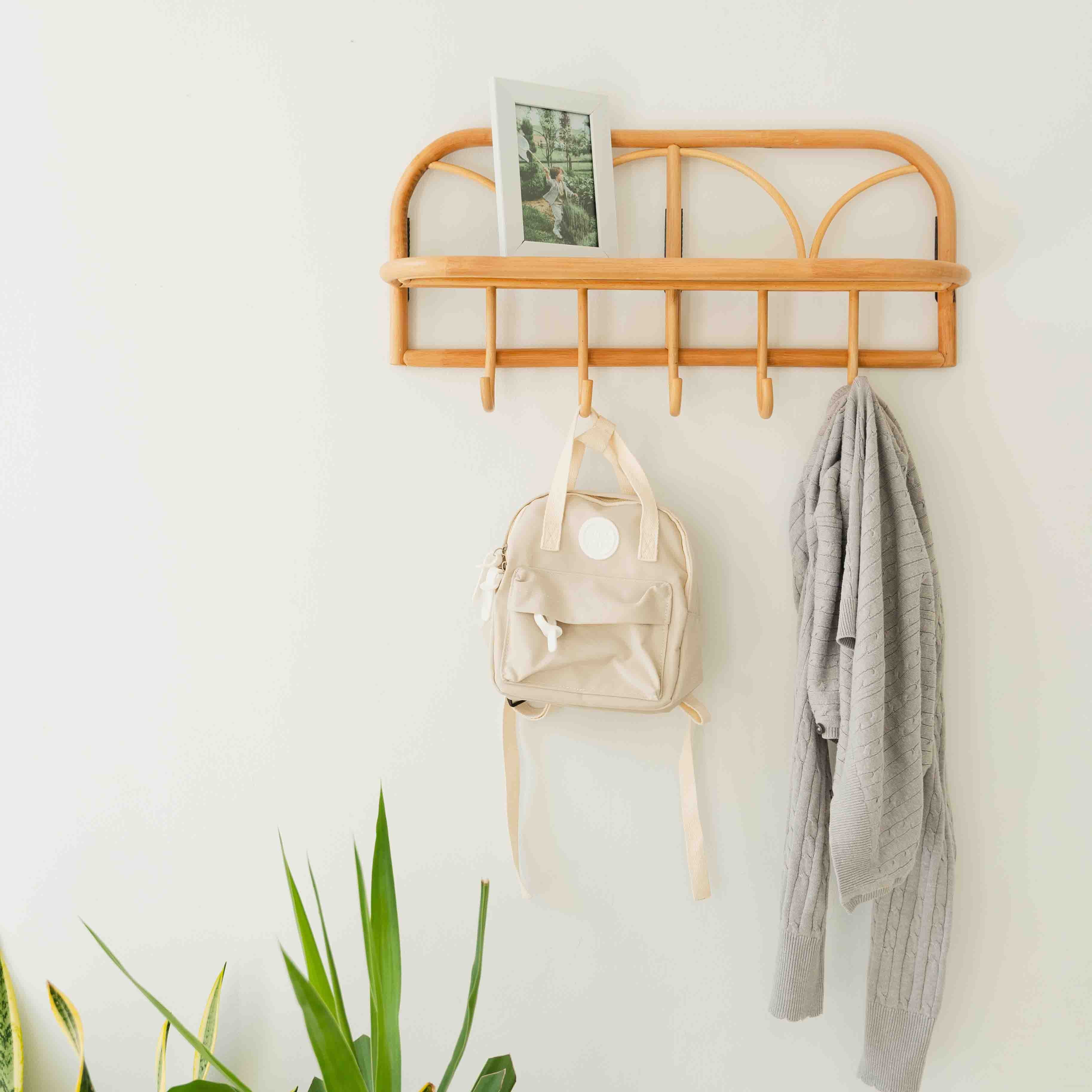 Eleanor Hanging Wall Shelf by MOMIJI mounted on the wall with framed shelving, clothes, and bags hanging from the hooks.