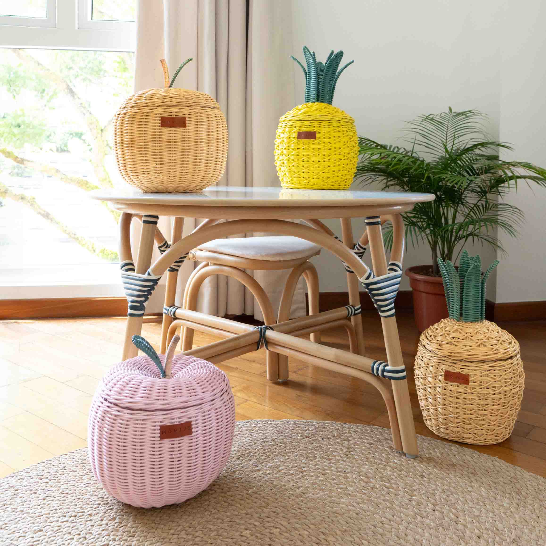 Fruits Rattan Storage Basket Collection in small size by MOMIJI arranged around a small table in a room with plants.