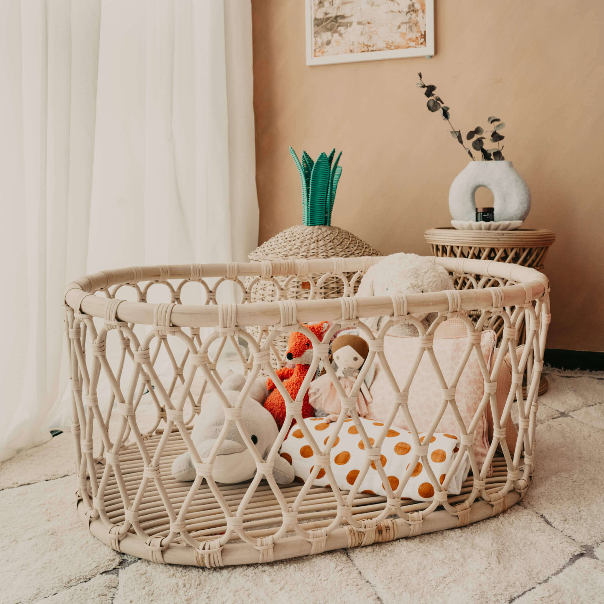 Gerhana Bassinet by MOMIJI without mattress, filled with dolls and placed on the floor in a styled room.