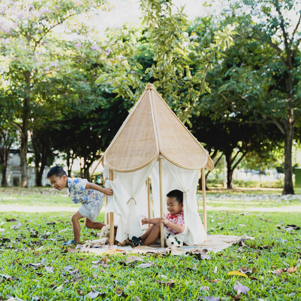 Two children having fun playing with the Leon Circus Tent by MOMIJI in an outdoor setting.