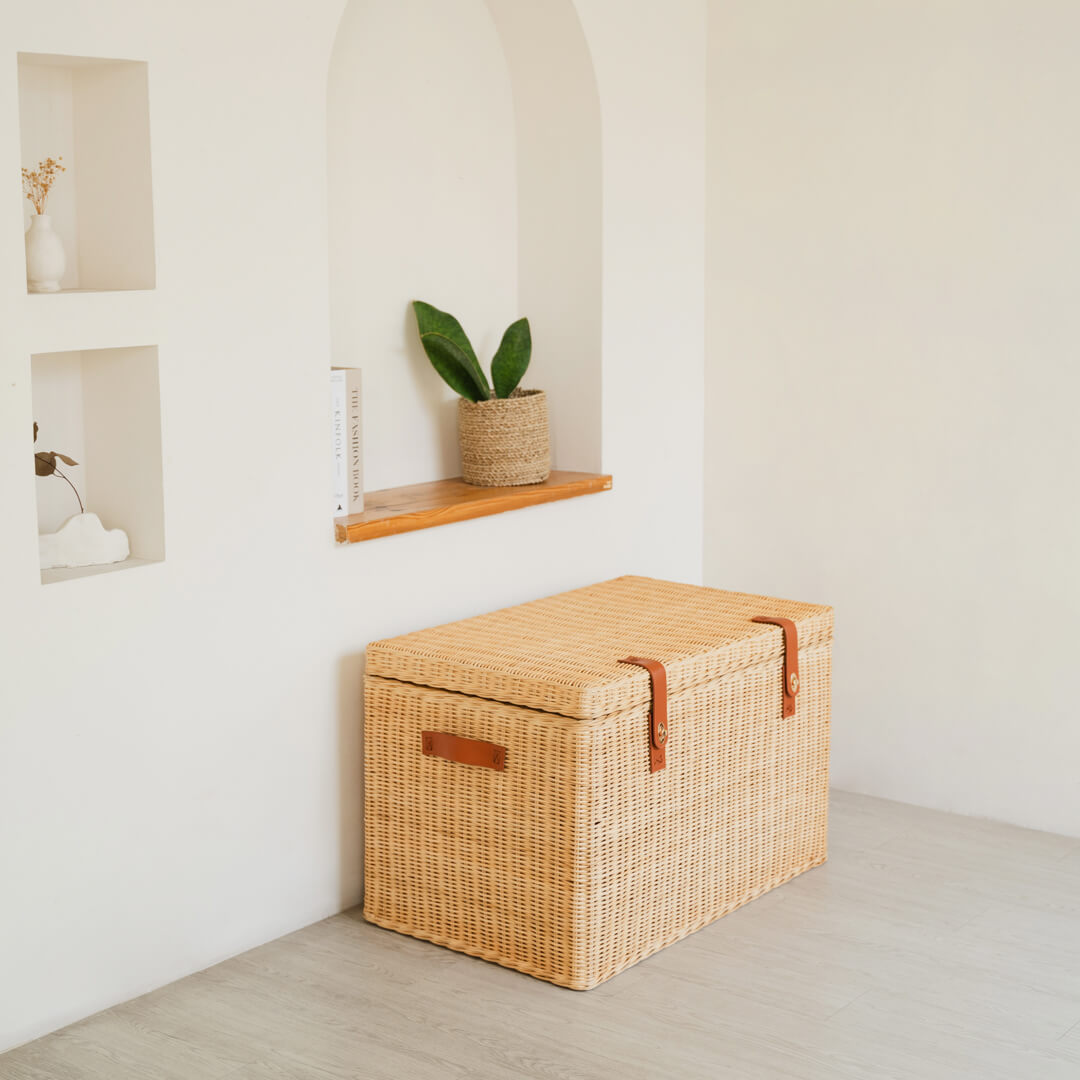 Side view of the handcrafted rattan wicker Leon Leather Trunk by MOMIJI, showing leather side handle and front lock for easy lifting.