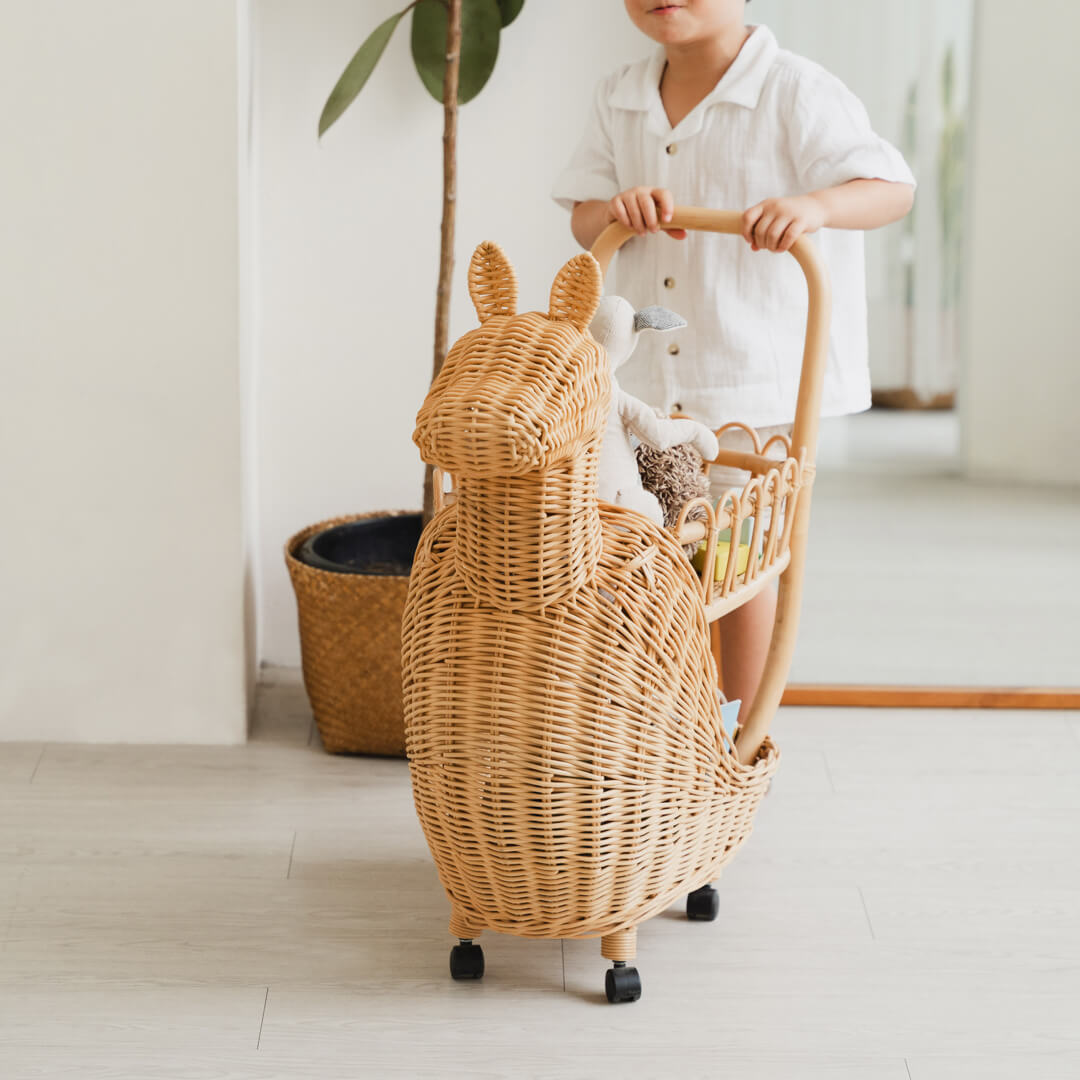 Close-up of the front section of the Llama Craft Trolley by MOMIJI filled with children’s toys, with indoor plants in the background.