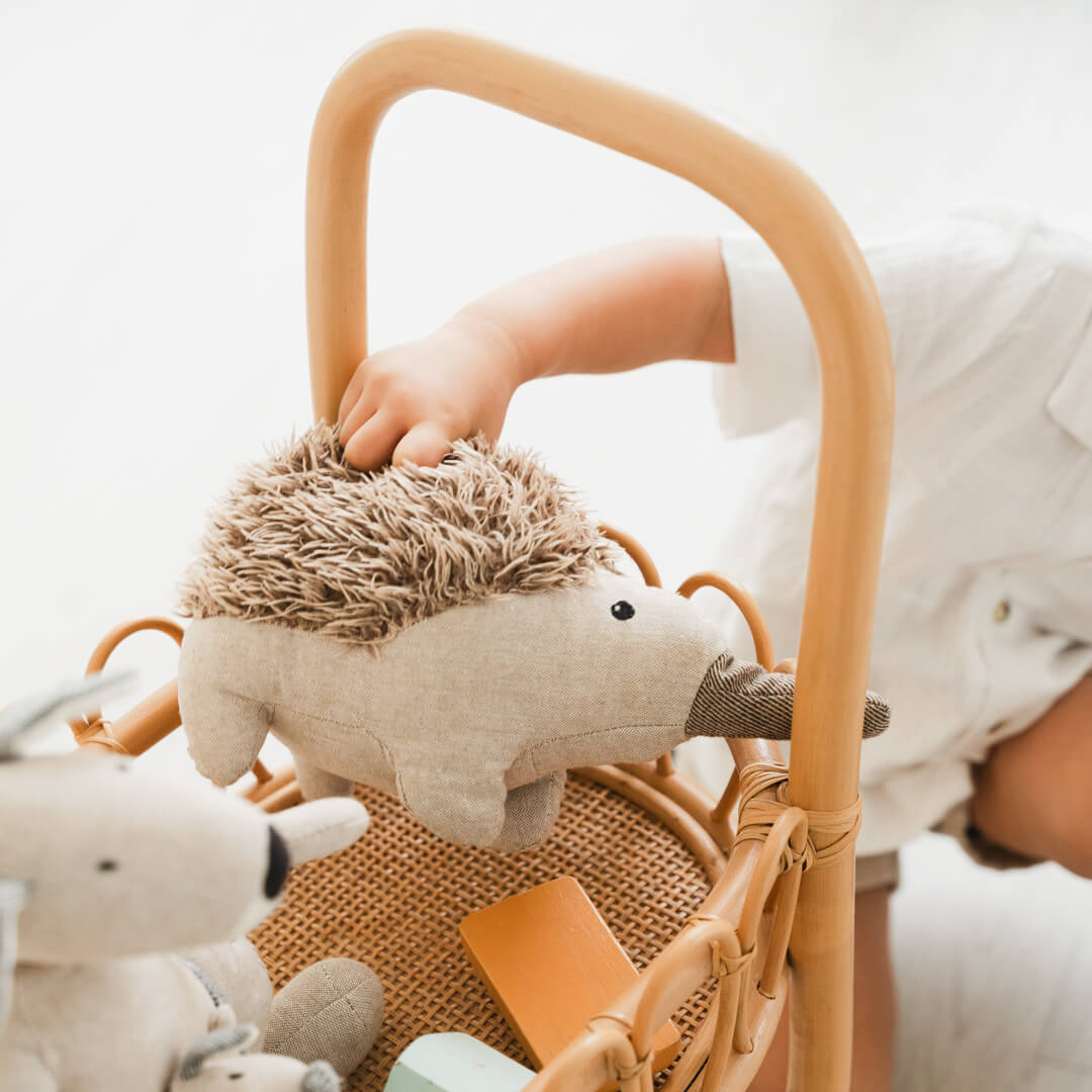 Close-up of a child placing stuffed toys into the top section of the Llama Craft Trolley by MOMIJI.
