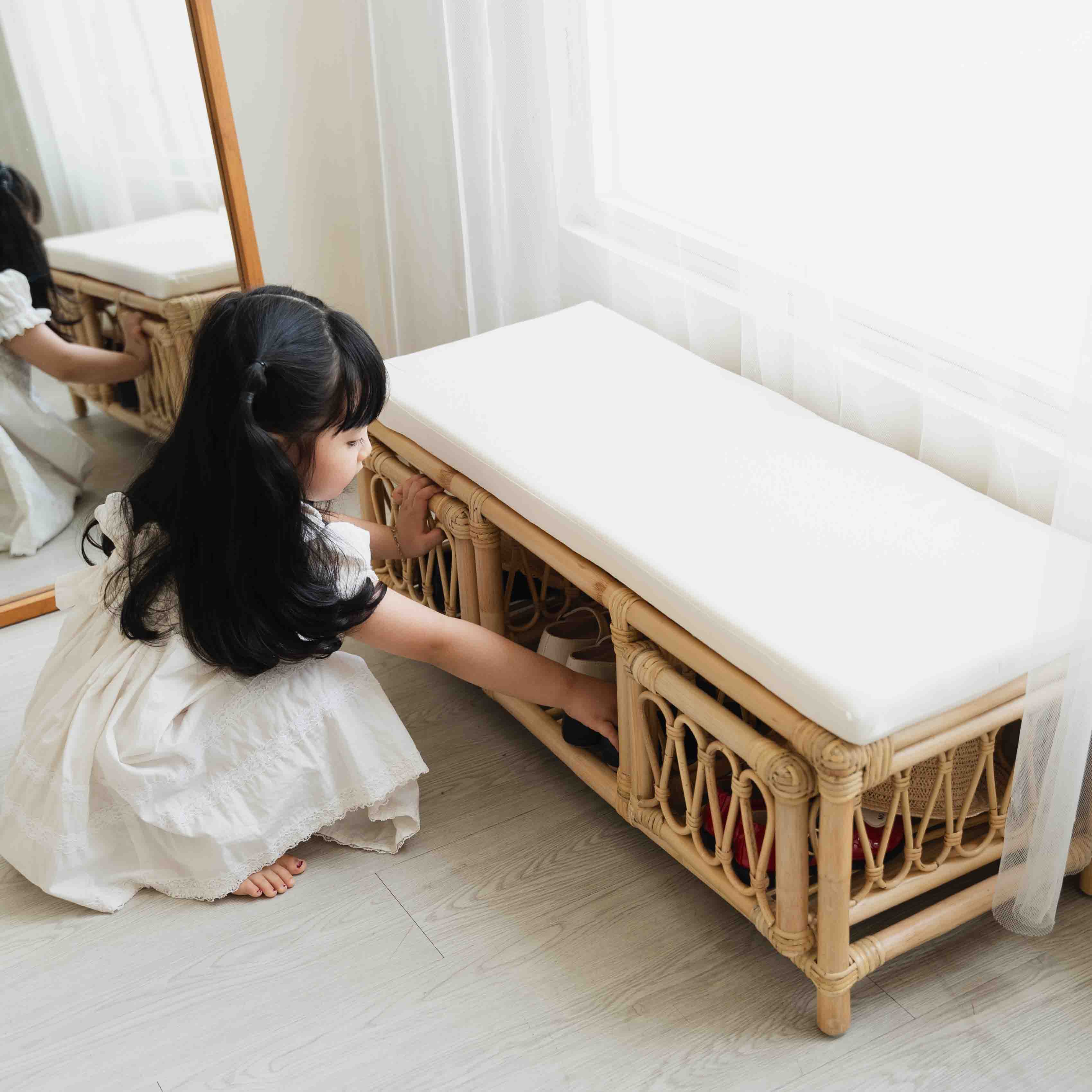 Child storing shoes in the lower storage compartment of the Luke Kids Bench by MOMIJI.