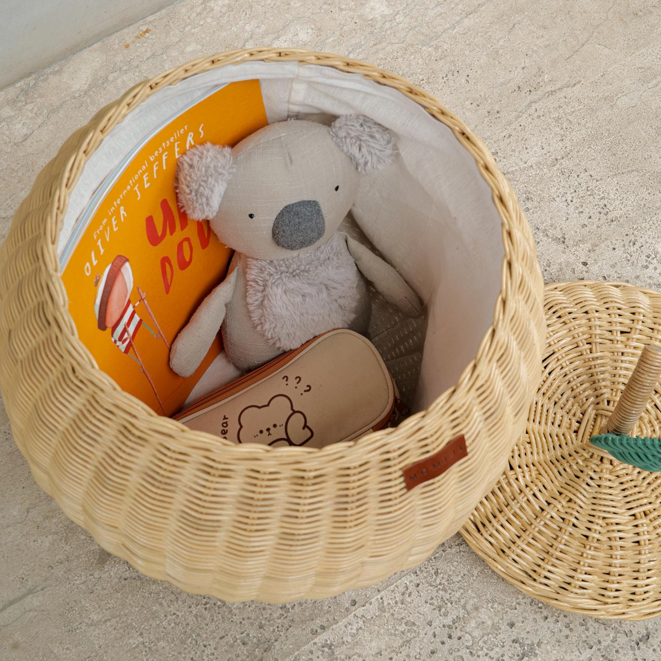 Natural apple rattan storage basket by MOMIJI with toys and books inside.