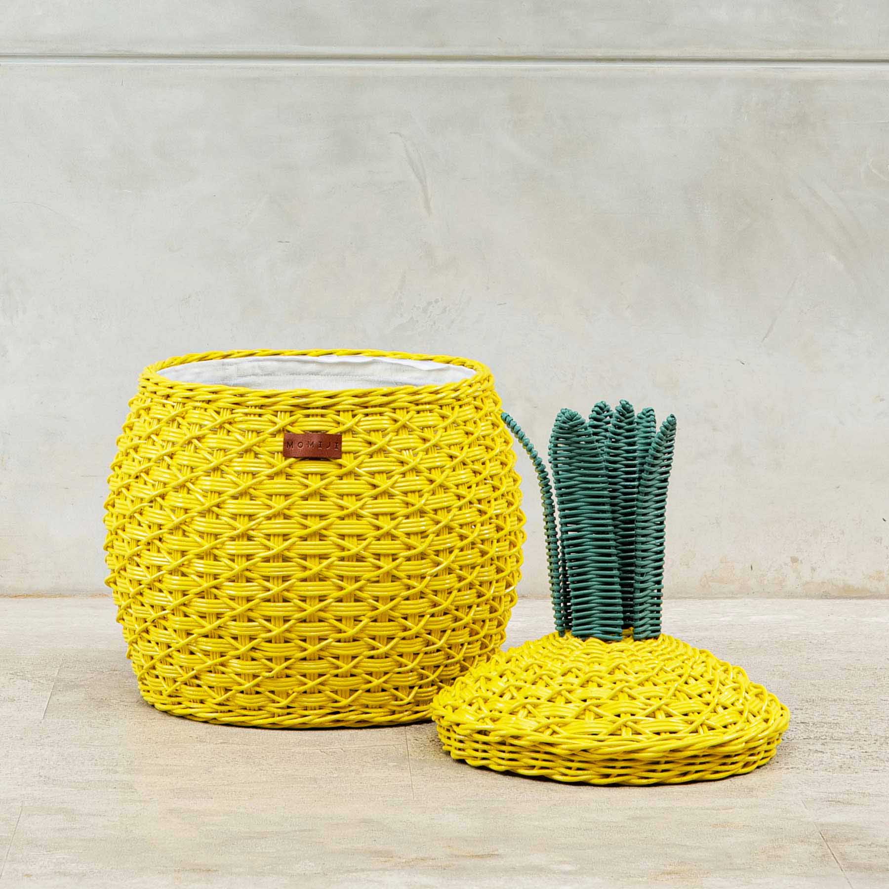 An opened yellow Pineapple Rattan Storage Basket in medium size with lid on the floor.