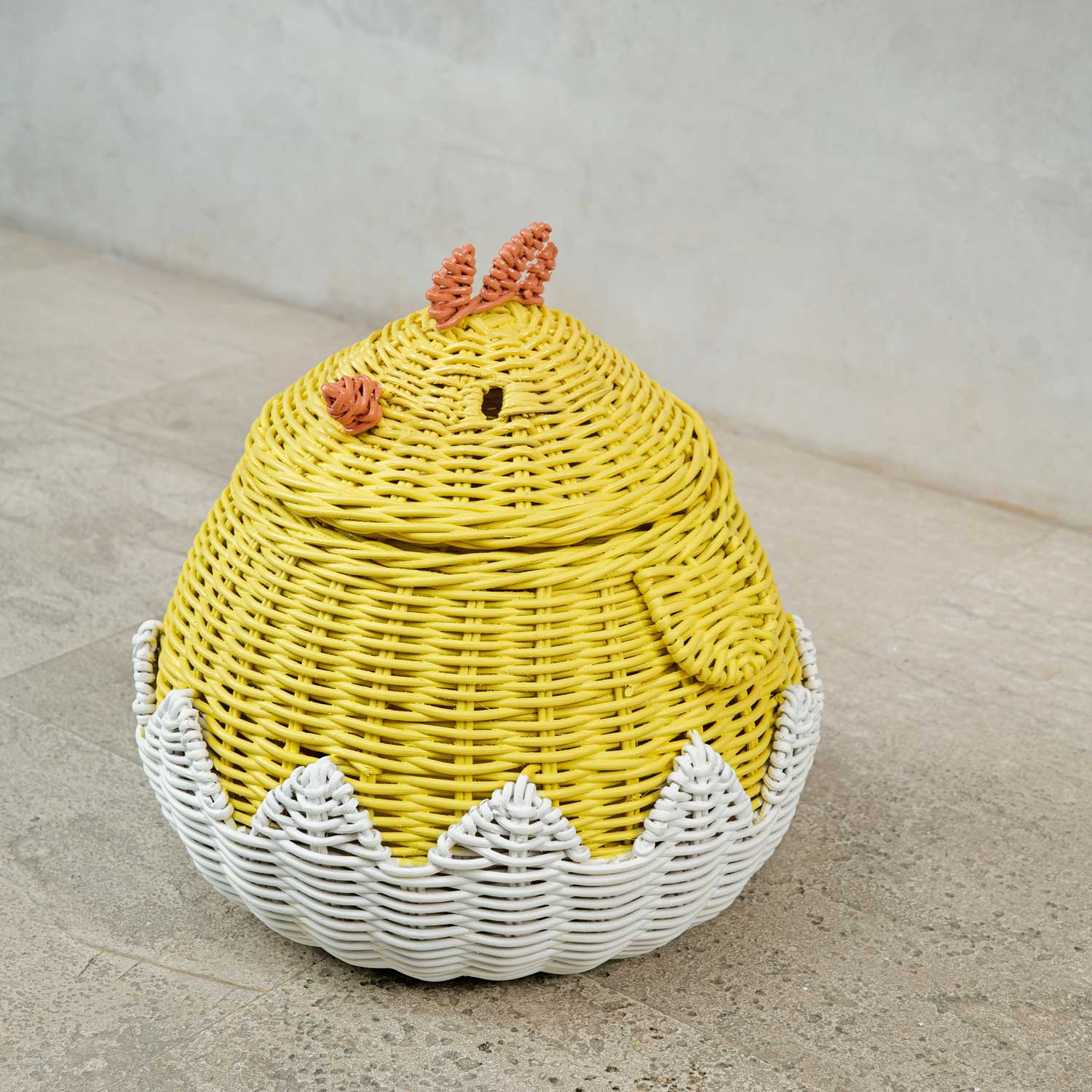 Chick Rattan Storage Basket by MOMIJI on a concrete floor.