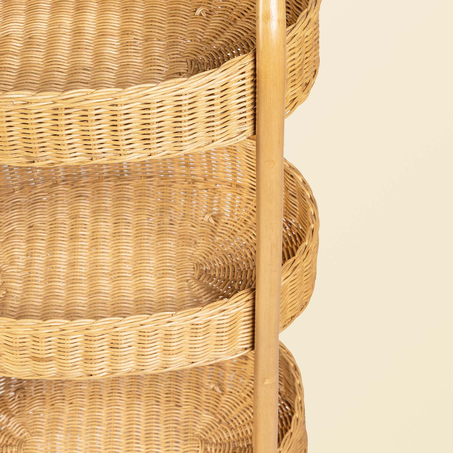 Close-up of handcrafted rattan wicker frame structure and three tier woven basket trays on a beige background