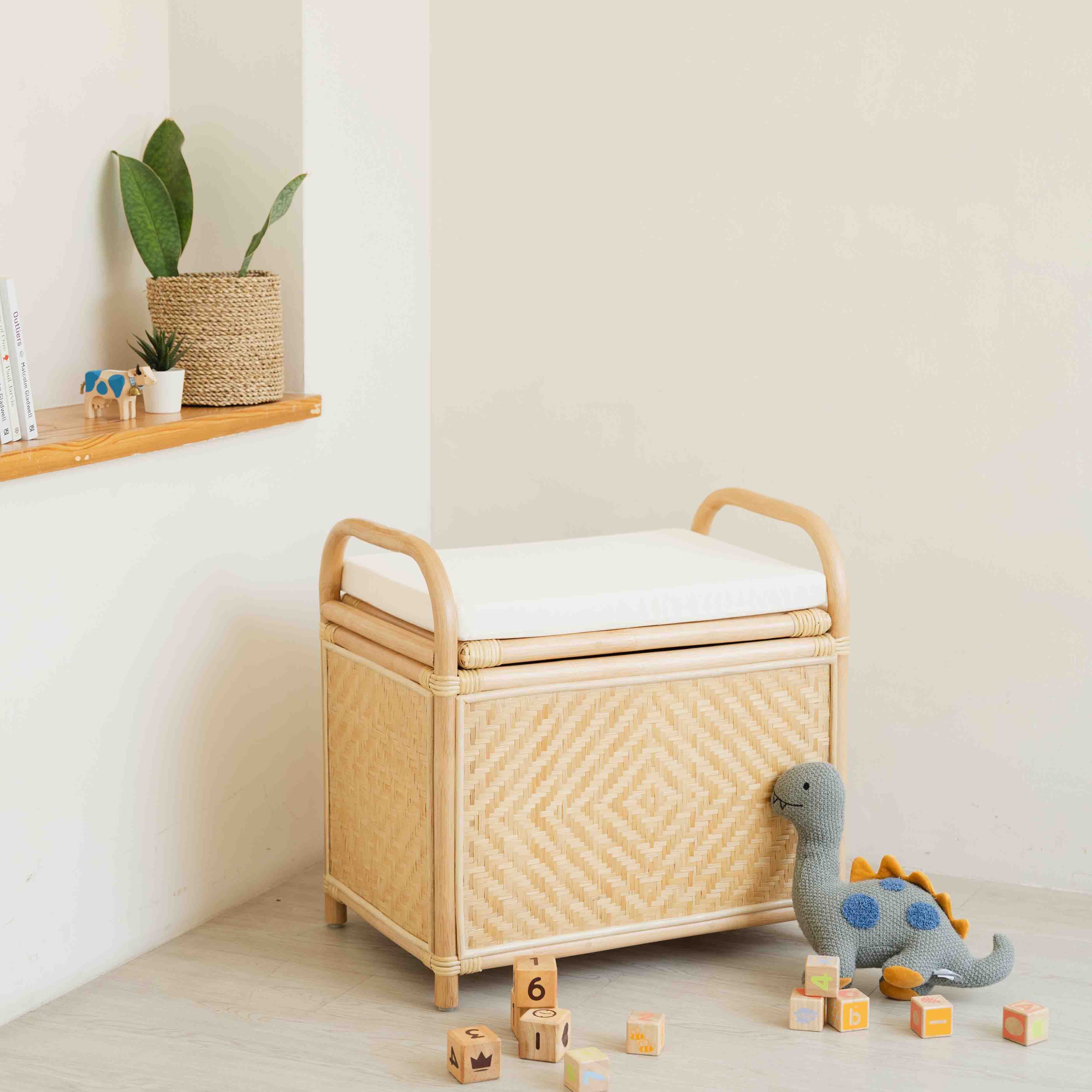 Angled view of the Mia Storage Bench by MOMIJI placed on a wooden floor with children’s toys.