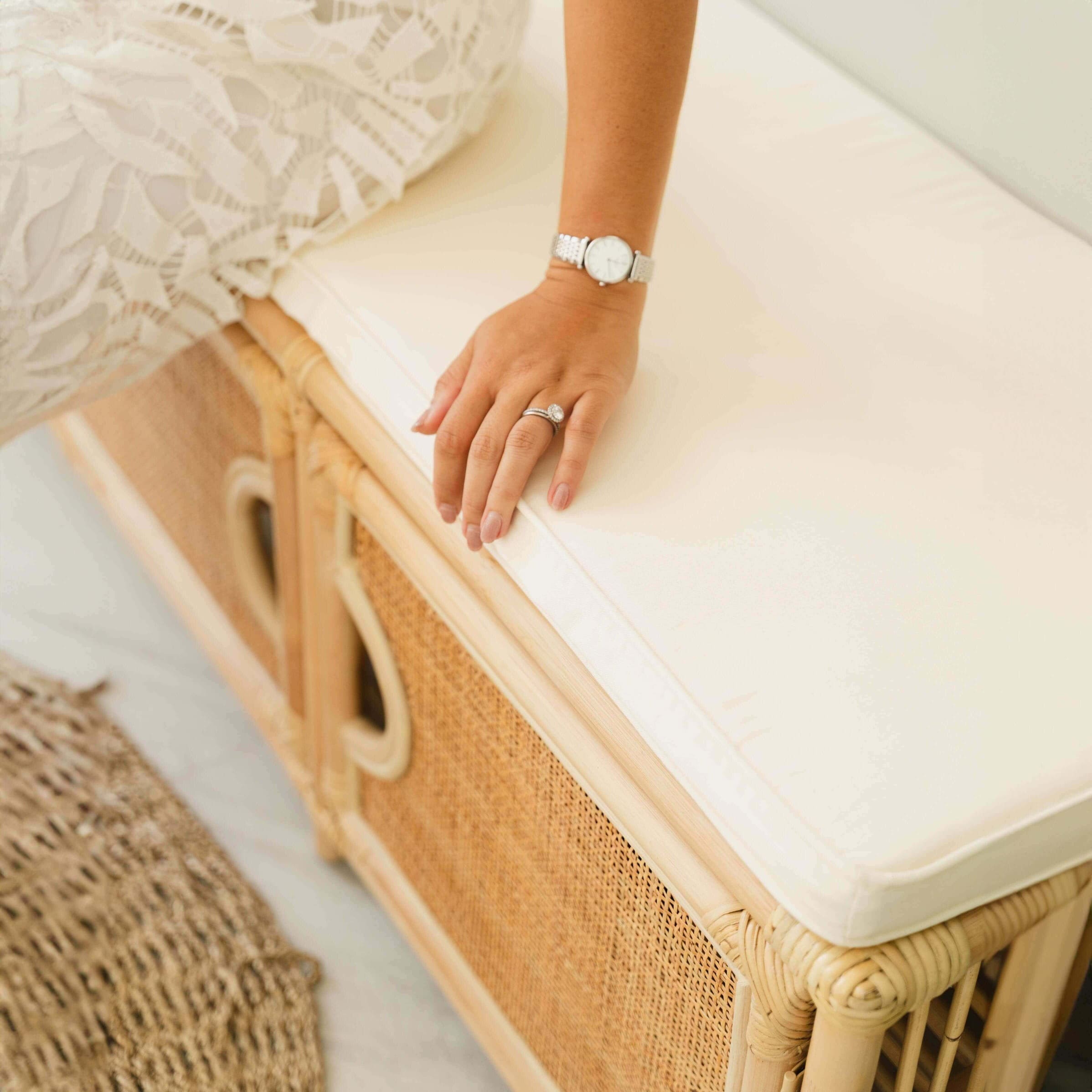 Top view of a woman seated on the Palma Shoe Cabinet by MOMIJI while holding the cushion.