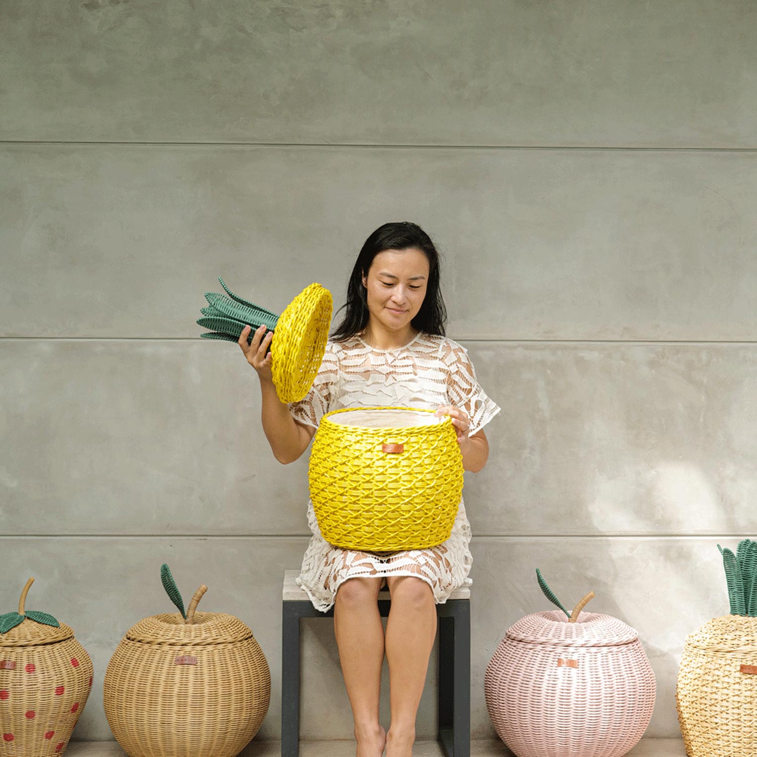 Woman Opening Yellow Pineapple Rattan Storage Basket in medium size by MOMIJI.