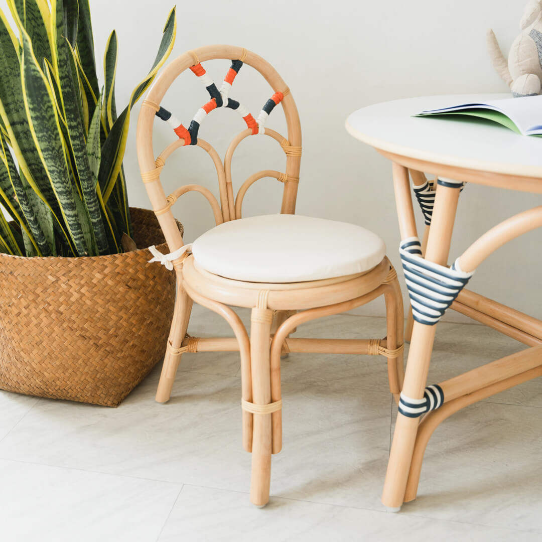 Handcrafted rattan wicker Quentin Kids Chair by MOMIJI styled with a white cushion and rattan table, designed for kids play and learning spaces.