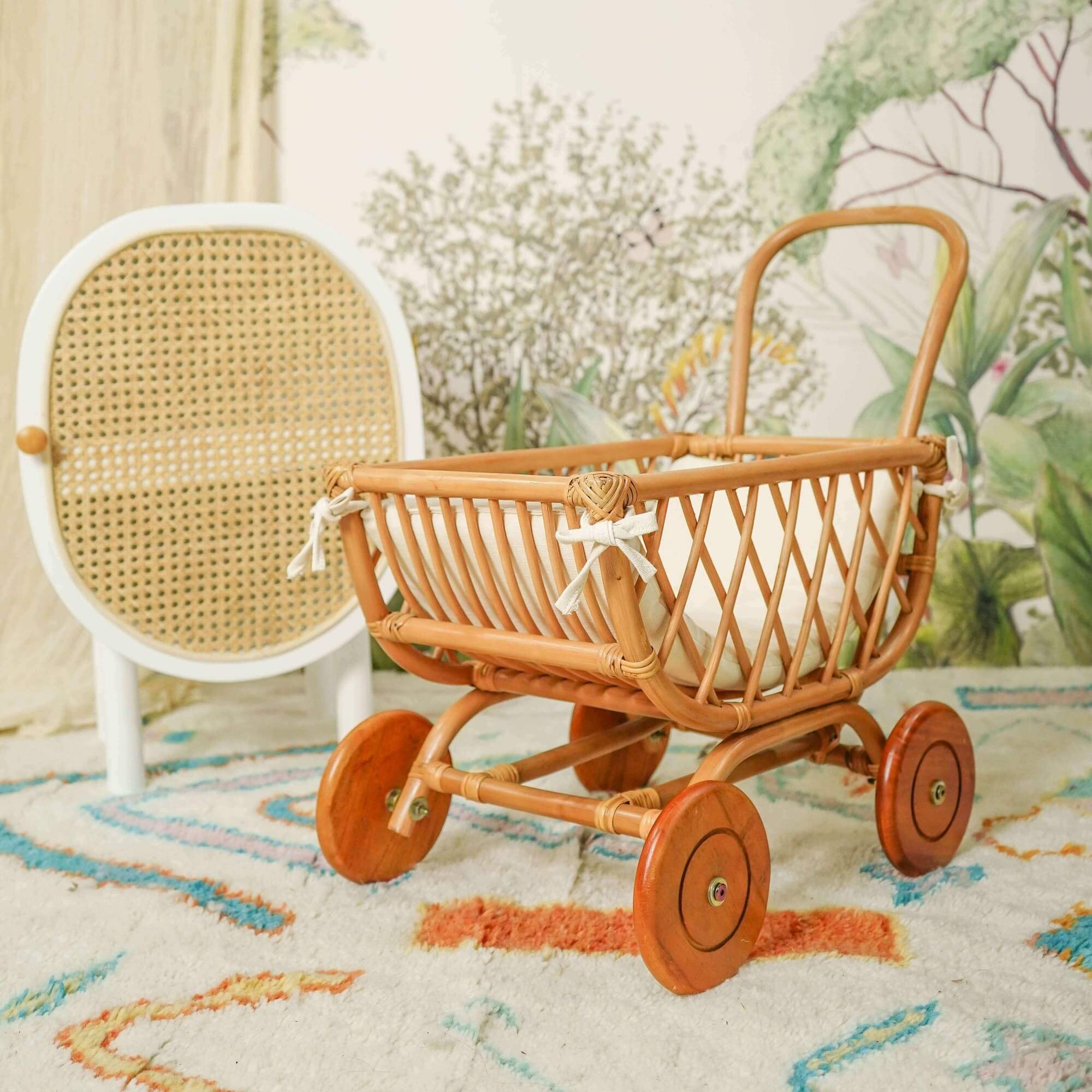 Rubble Toy Trolley by MOMIJI placed on a rug with a white mattress in a room with floral wallpaper.