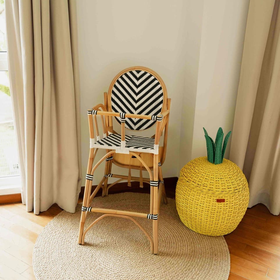 Front view of the Handcrafted rattan wicker Tumbuh Kids High Chair by MOMIJI without the tray attached, with the tray stored behind.