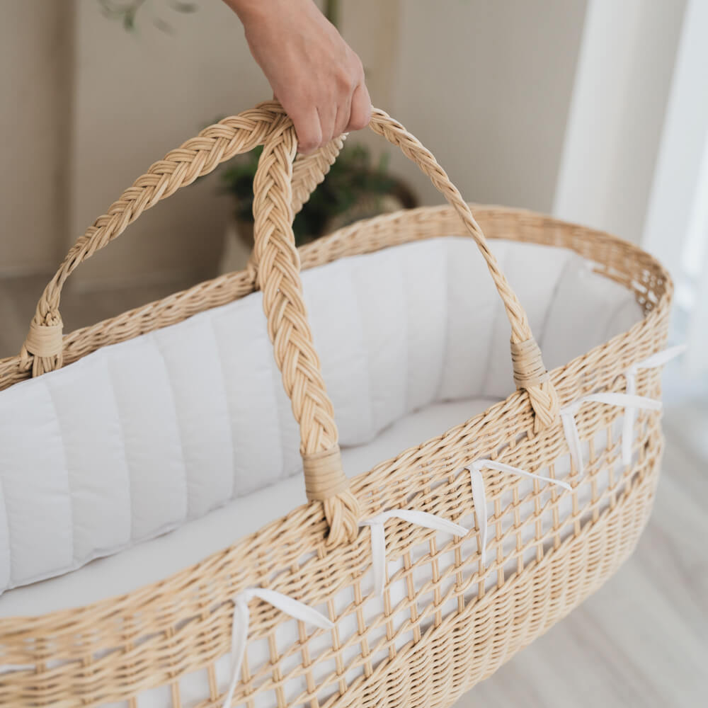 Woman holding the Vera Moses Rattan Basket by MOMIJI indoors, showcasing the fully handwoven rattan construction of the basket and handles.