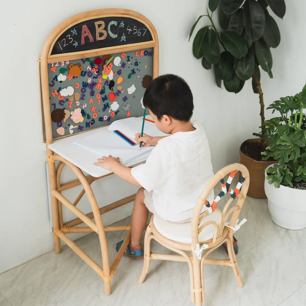 Child sitting and studying using the 3-in-1 furniture by MOMIJI in a room with plants.