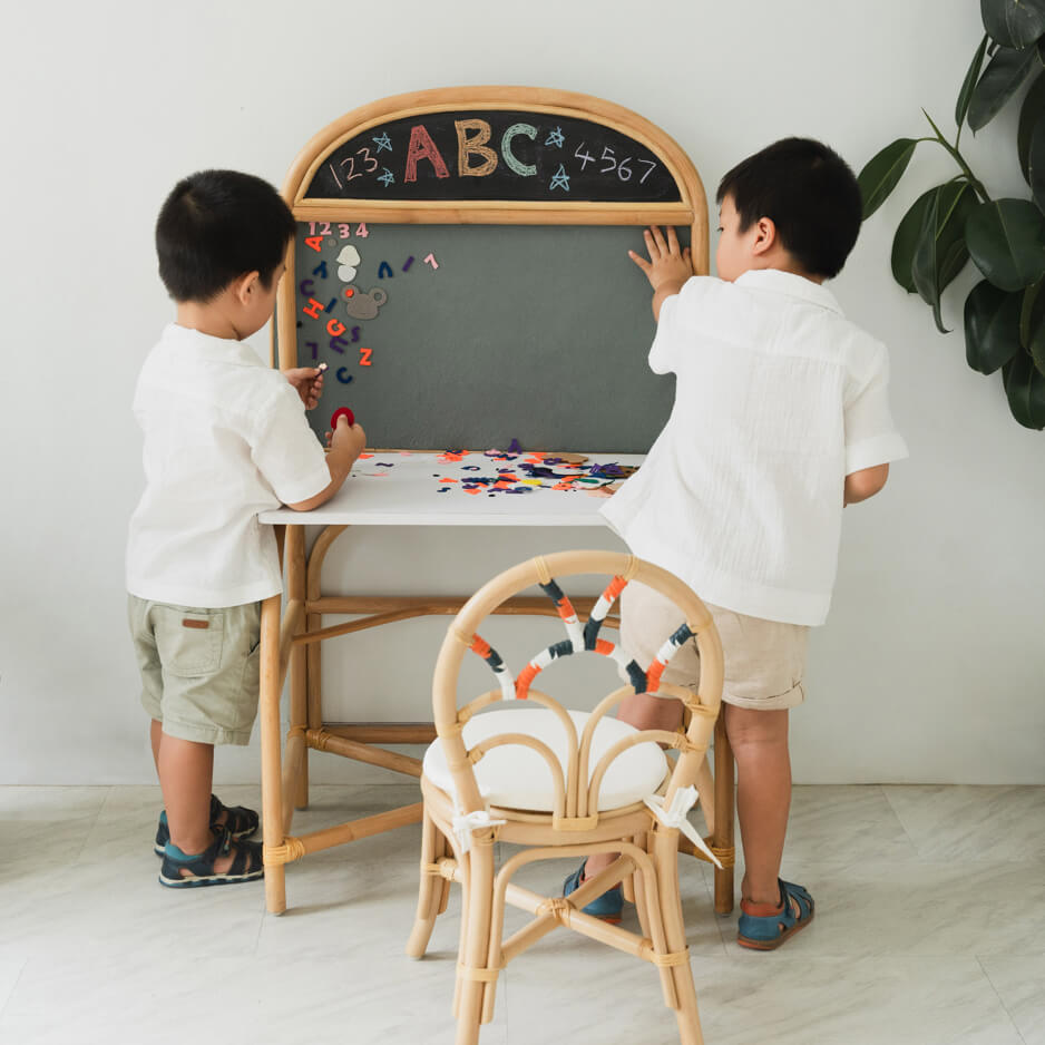 Two children studying together using the desk and board mode of the 3-in-1 furniture by MOMIJI.