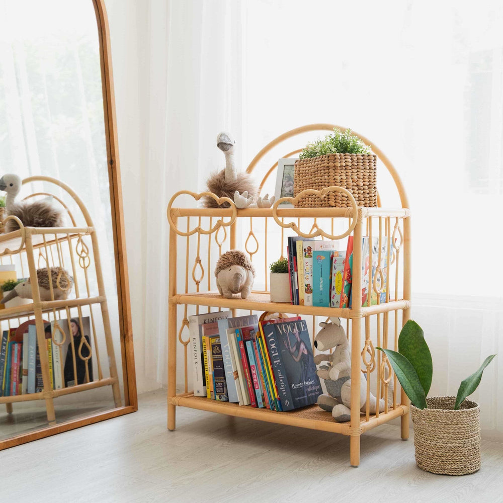Angled view of the After the Rain Shelf by MOMIJI filled with children’s books and toys in a room with flowers.