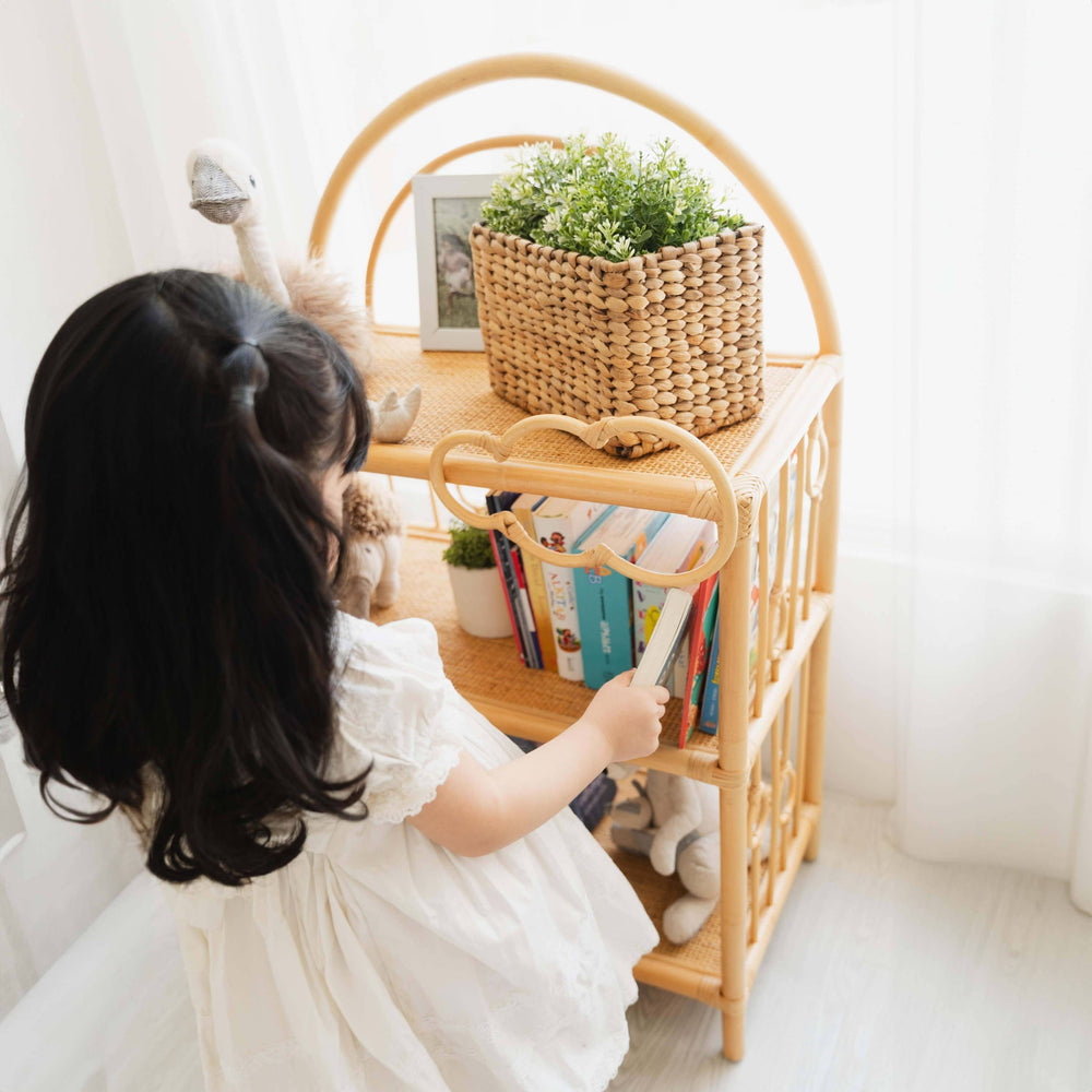 Child taking a book from the After the Rain Shelf by MOMIJI in an indoor setting.