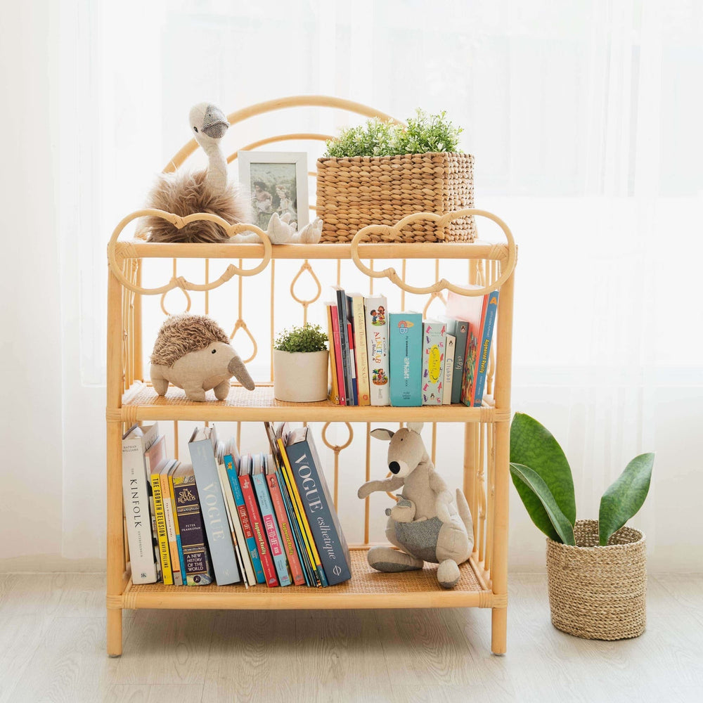 After the Rain Shelf by MOMIJI filled with books, toys, and plants in a room with flowers placed in a rattan basket.