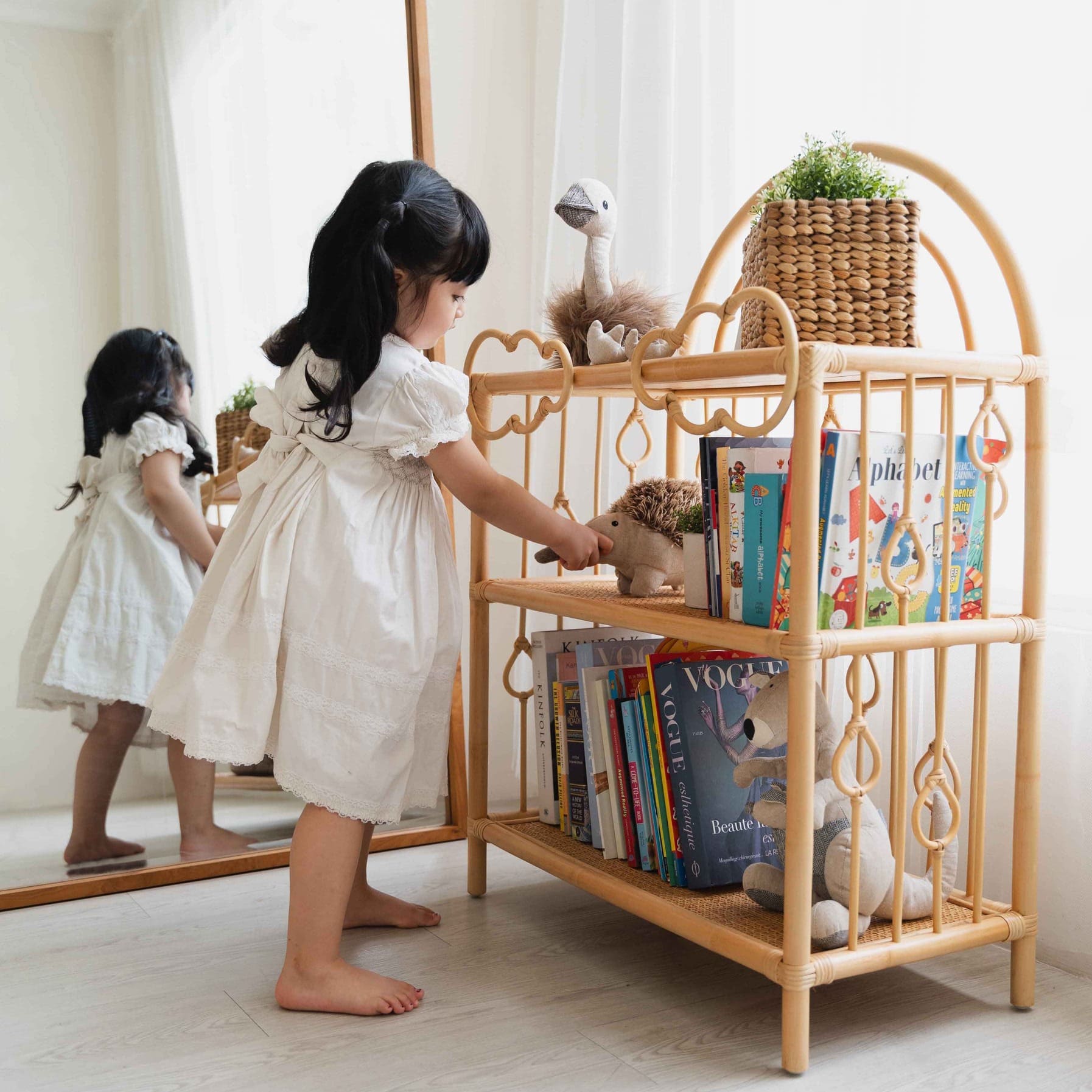 Child taking a doll from the After the Rain Shelf by MOMIJI in a room with a mirror.