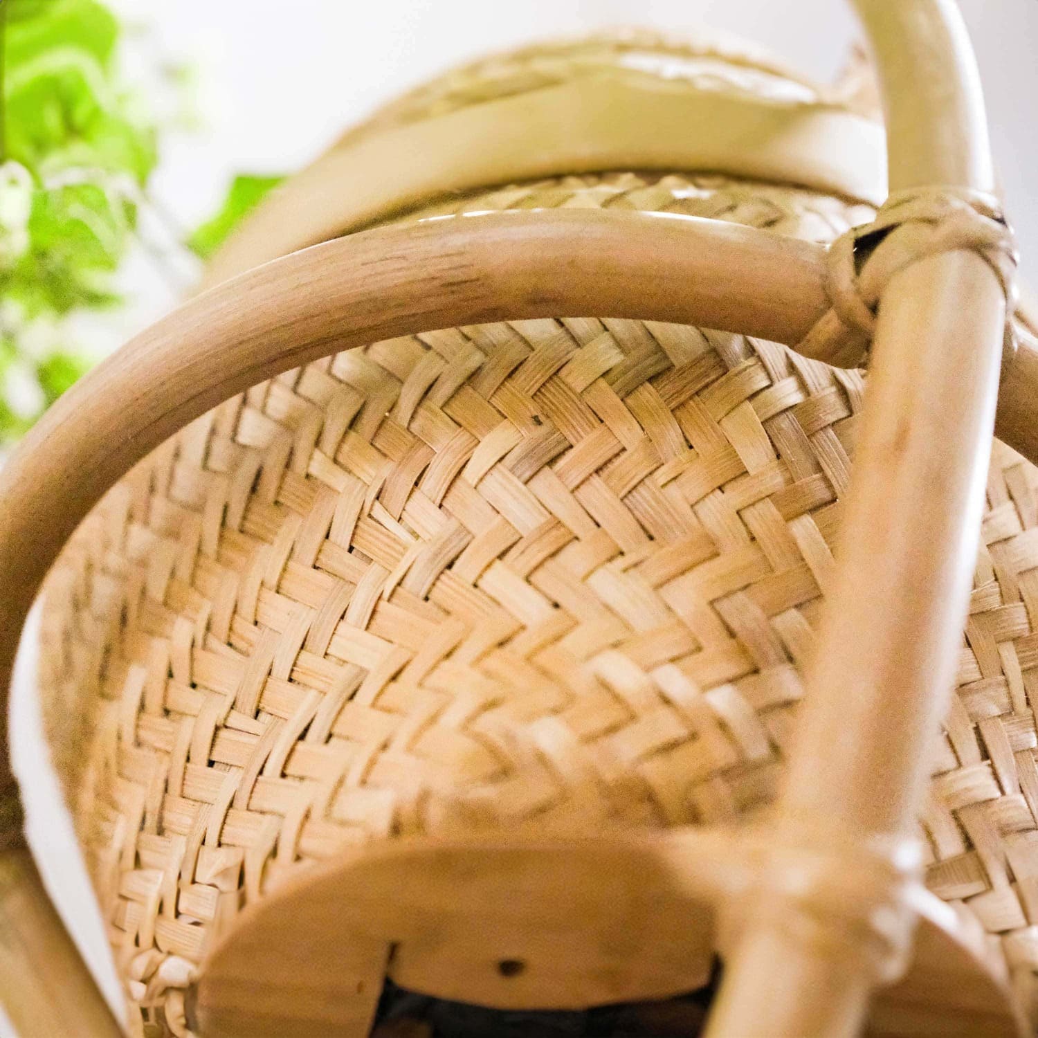 Close-up of the woven basket detail of the Almond Hanging Planter by MOMIJI used to hold a plant pot.