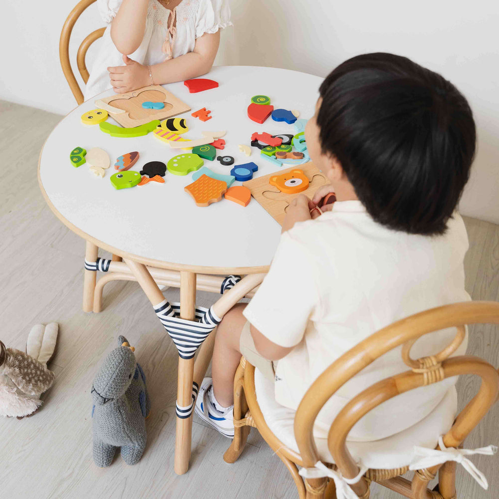 Two children playing with colorful puzzle toys while sitting on the Amélie Kids Chair by MOMIJI.