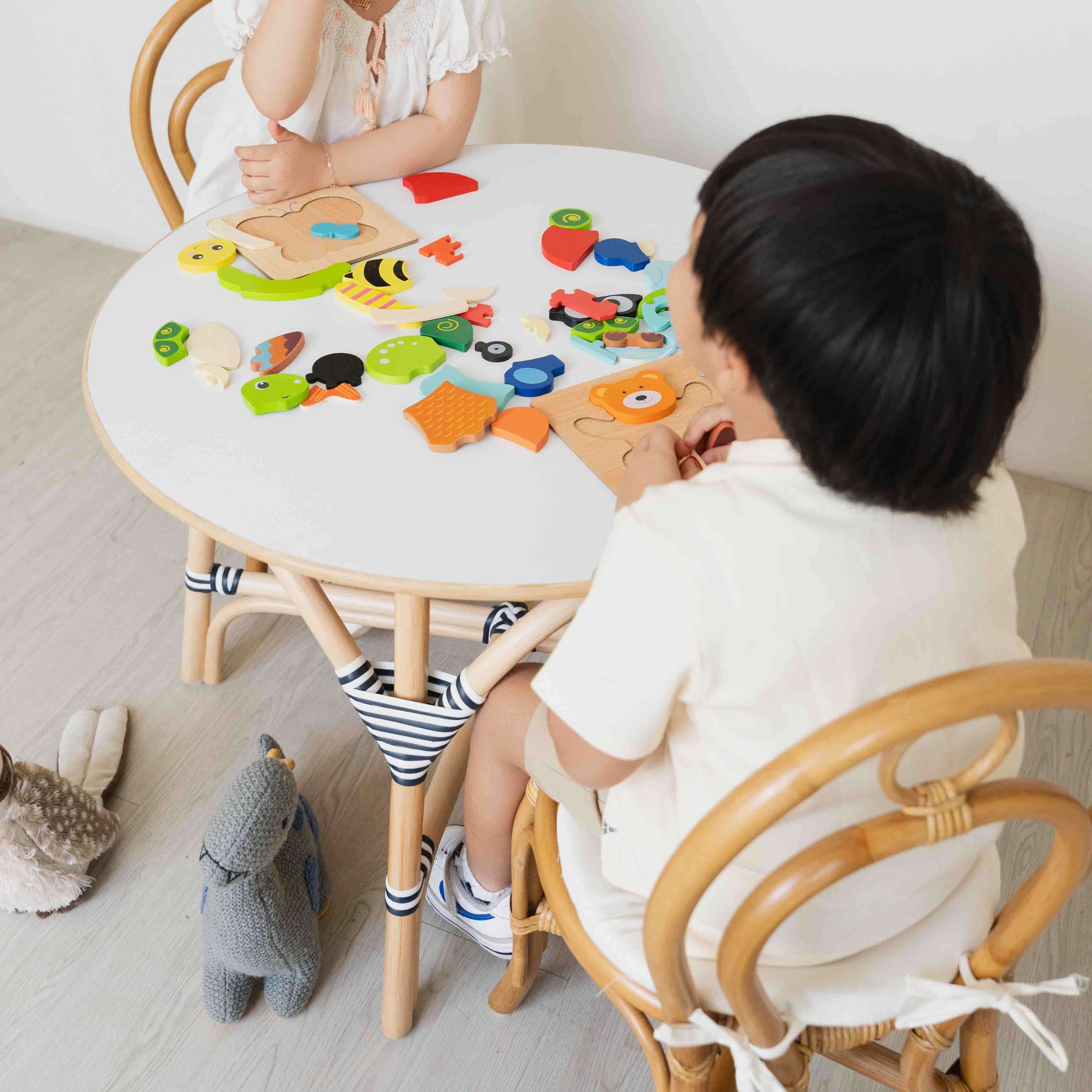 Two children playing with colorful puzzle toys while sitting on the Amélie Kids Chair by MOMIJI.