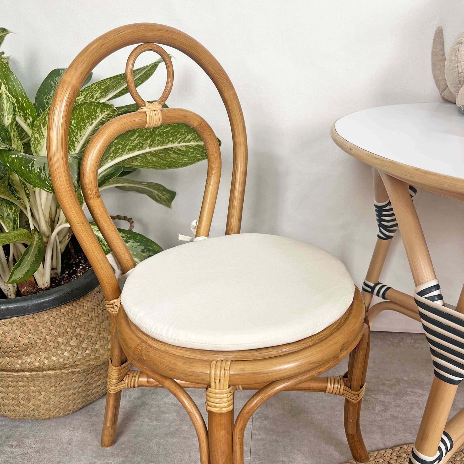 Close-up of the seat and backrest detail of the Amélie Kids Chair by MOMIJI in a room with potted plants.
