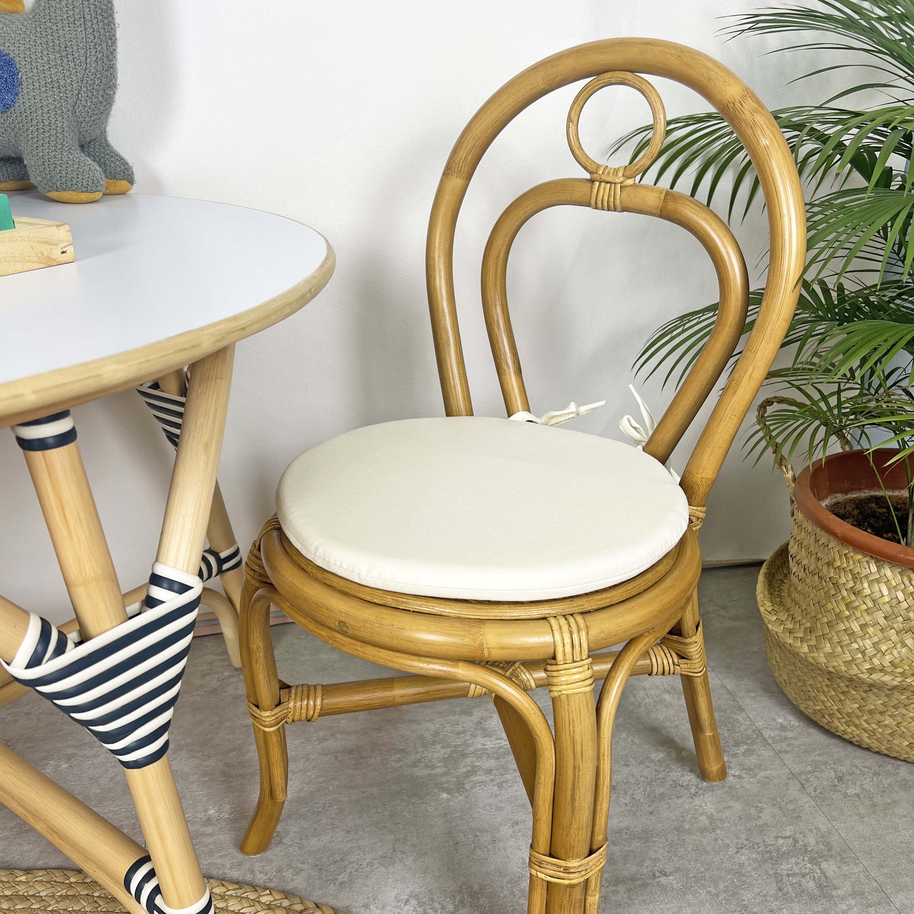 Front view of the handcrafted rattan wicker Amélie Kids Chair by MOMIJI, highlighting the comfortable removable cushion for children's seating and the supportive child-safe backrest design, showcasing natural rattan craftsmanship in a bright indoor setting.
