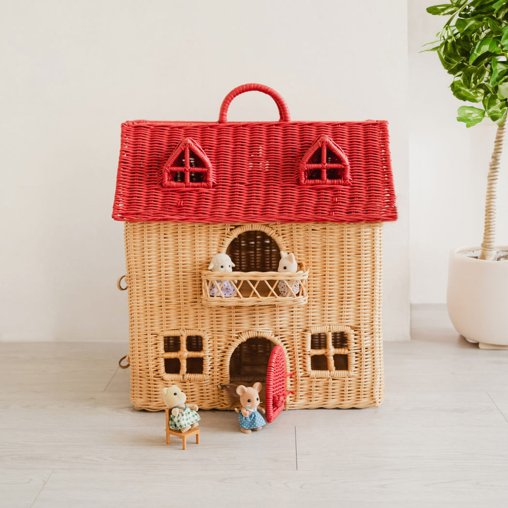 Wicker Amy Dollhouse Tote by MOMIJI styled with small figurines on a wooden floor, placed in a cozy room with indoor plants.