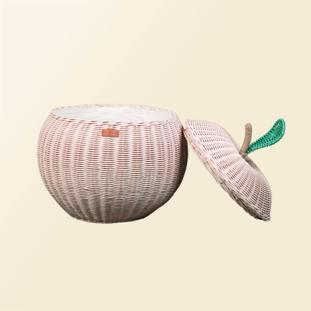 Front view of an opened pink apple rattan storage basket by MOMIJI with lid leaning beside the basket.