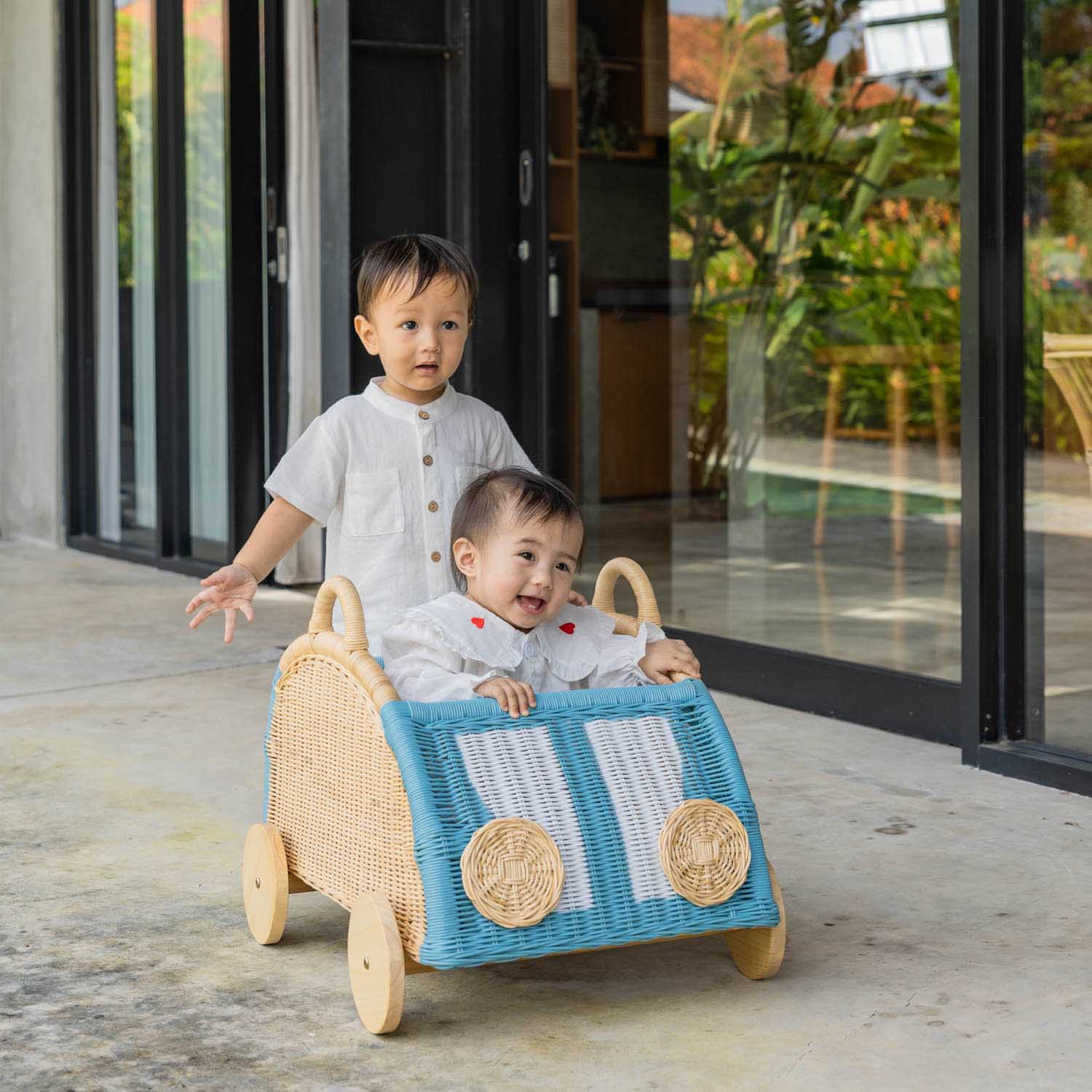 Two children having fun while playing with the Archie Storage Wagon by MOMIJI outdoors.