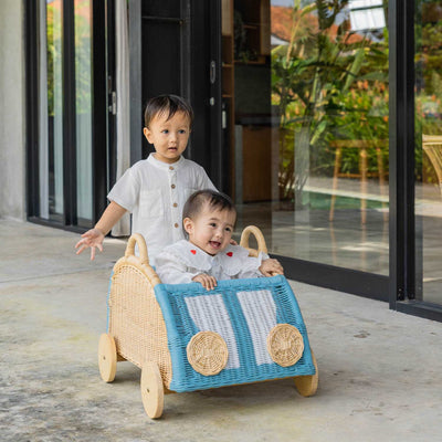 Two children having fun playing with the handcrafted rattan wicker Archie Storage Wagon by MOMIJI outdoors.