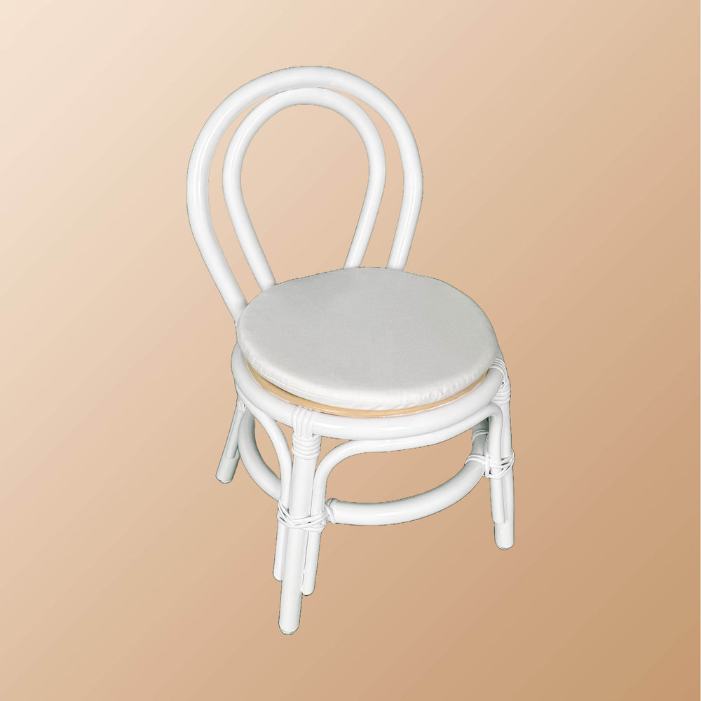Angled view of the Aulia Kids Chair by MOMIJI with a white cushion, highlighting the white rattan frame.