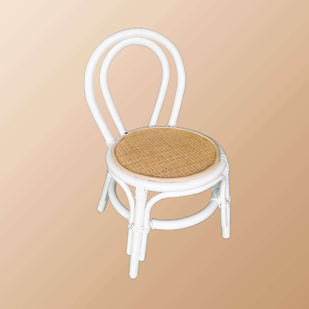 Angled view of the Aulia Kids Chair by MOMIJI without a cushion, featuring a white rattan frame and a natural handwoven rattan seat.