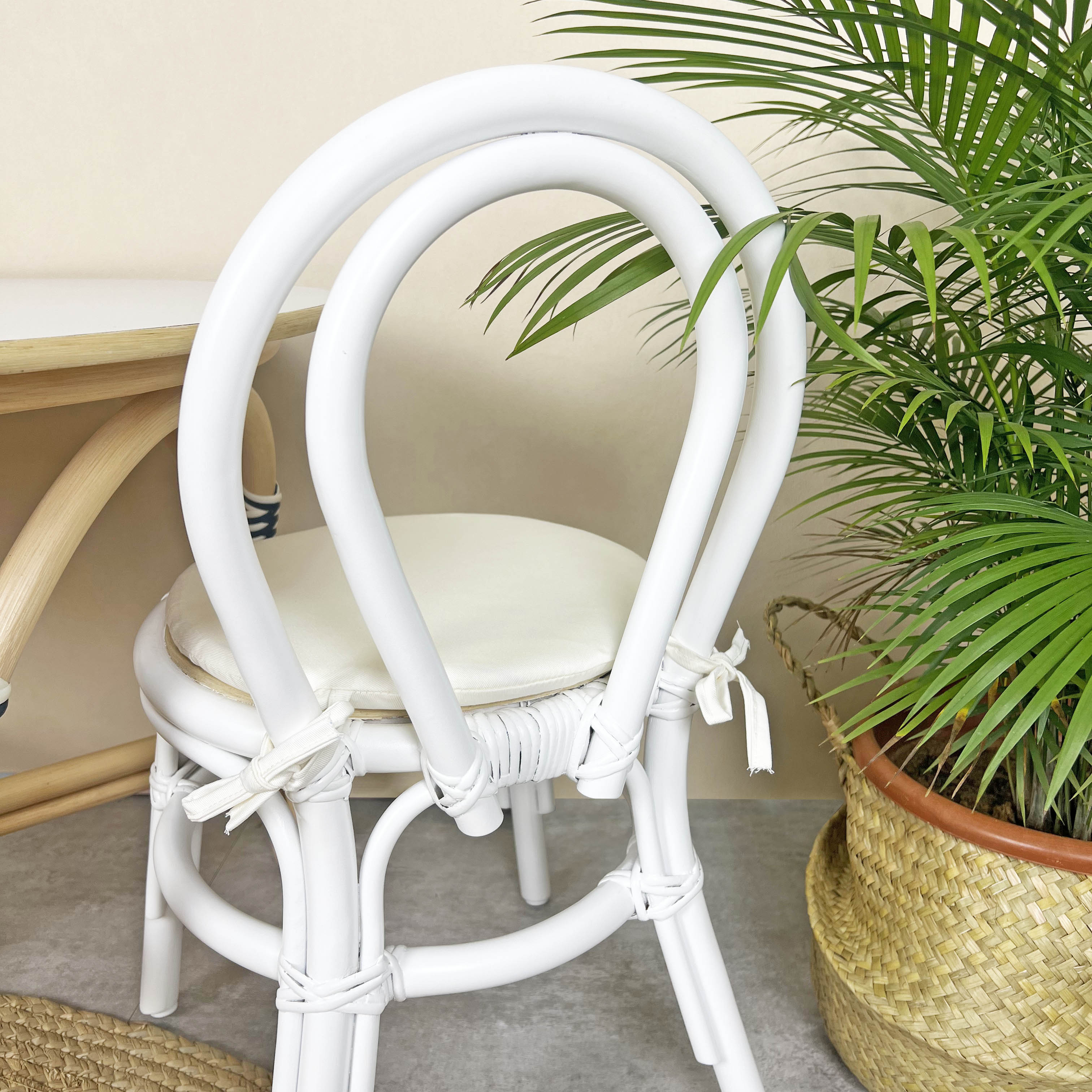 Back view of the Aulia Kids Chair by MOMIJI in an indoor setting with an Aulia Kids Table and a potted plant, highlighting the sturdy white rattan backrest designed with safe and supportive structure for children.
