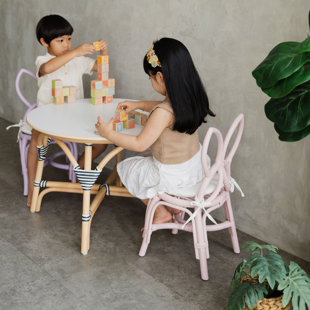 Two children sitting on Pink and Purple Butterfly Kids Chairs by MOMIJI, playing with colourful blocks at an Aulia Kids Table in a playful children's room.
