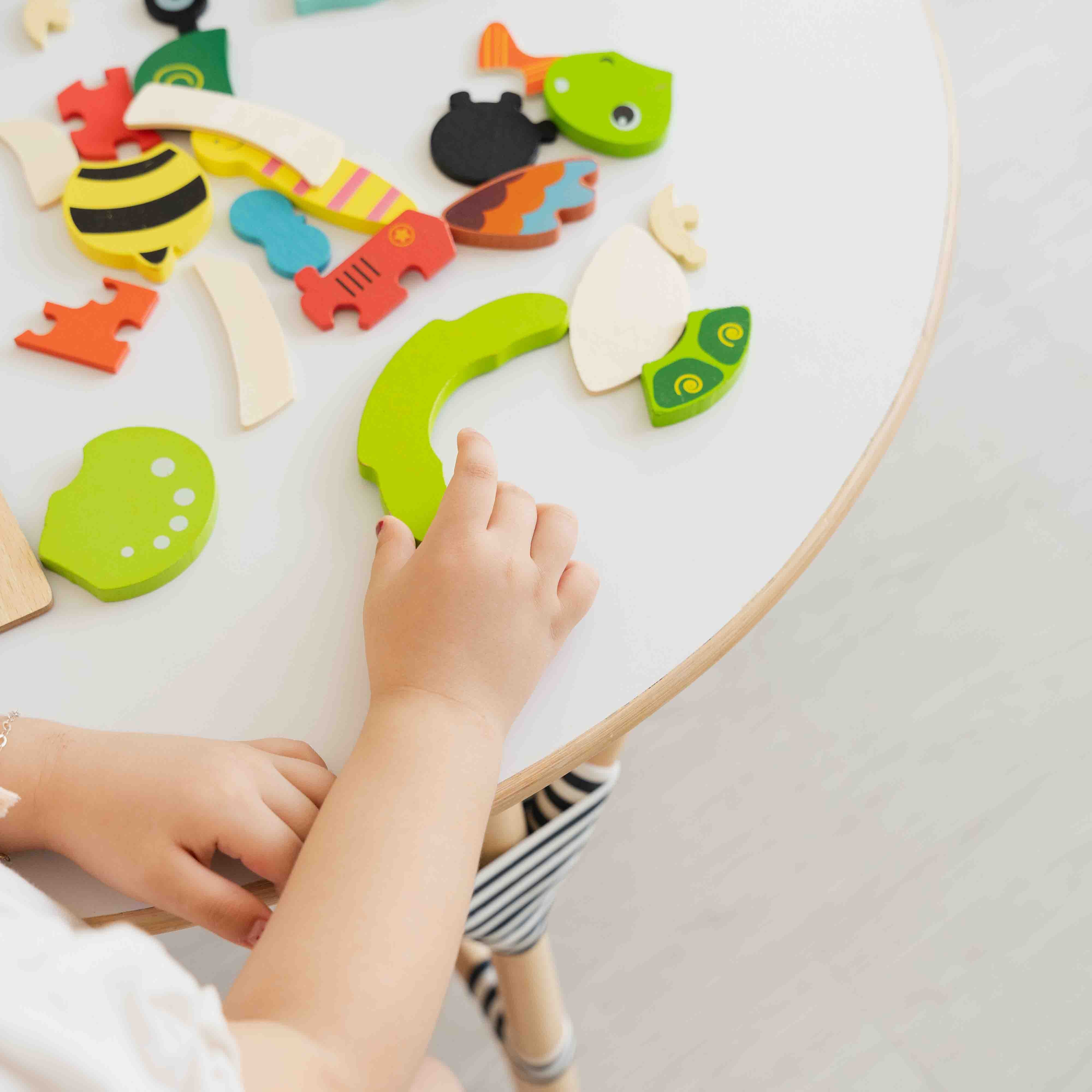 Handcrafted rattan wicker Aulia Kids Table (Medium) styled with colourful wooden puzzle pieces as a child plays at the table, creates a fun and engaging play and learning space for children.